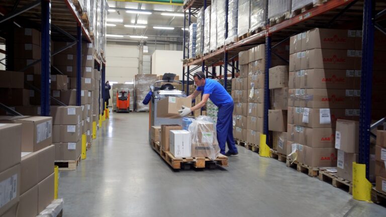 A huge room for a warehouse. Creative. Huge parcels next to which specially equipped cars drive and